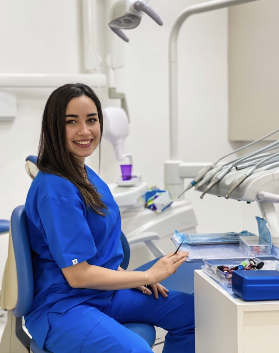 Dr Maryam Chikhaoui, chirurgien-dentiste en tenue médicale bleue, souriante dans son cabinet dentaire moderne de Val Fleuri Casablanca